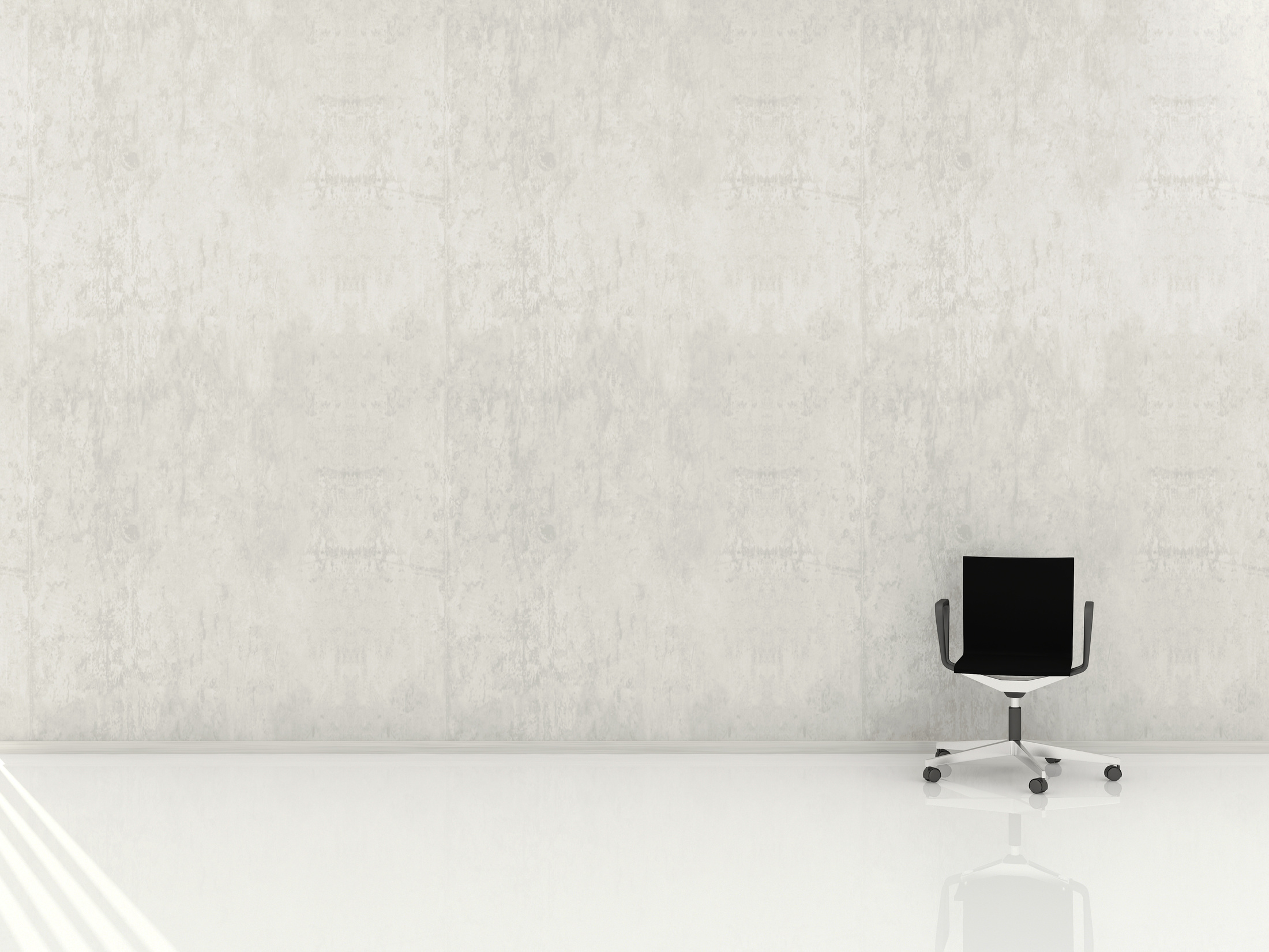 A plain white wall and floor with a small office chair
